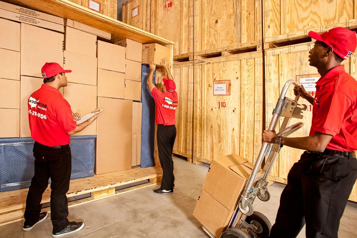 Two Nationwide Van Lines movers in the storage warehouse with wooden vaults