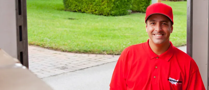Smiling Nationwide Van Lines mover in a red company cap and polo
