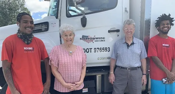 Two Nationwide Van Lines movers with an older couple in front of the truck