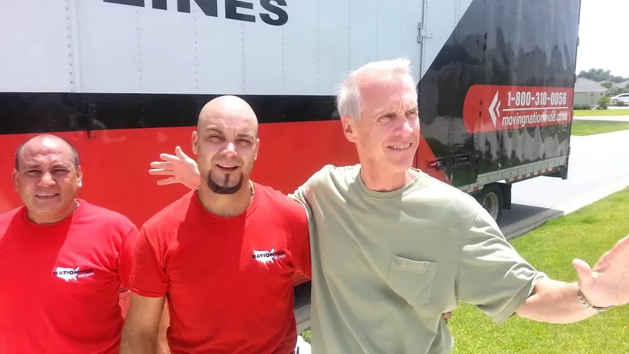 Two Nationwide crew members with a happy customer in front of the truck